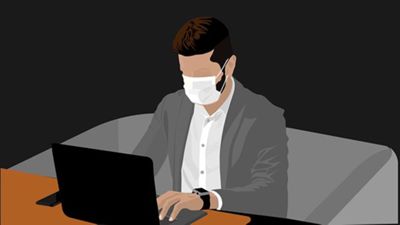 Homme avec un masque devant un ordinateur